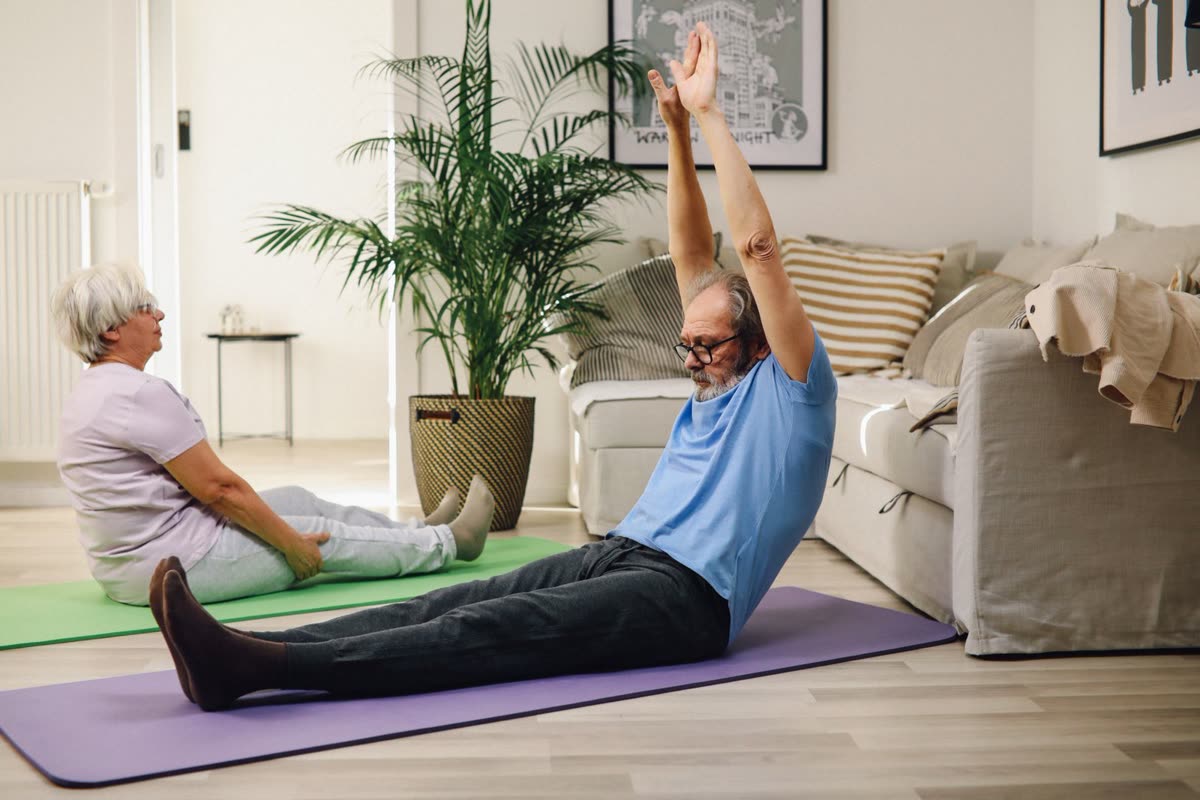 Two people training at home in a bright living room, working at their own pace.